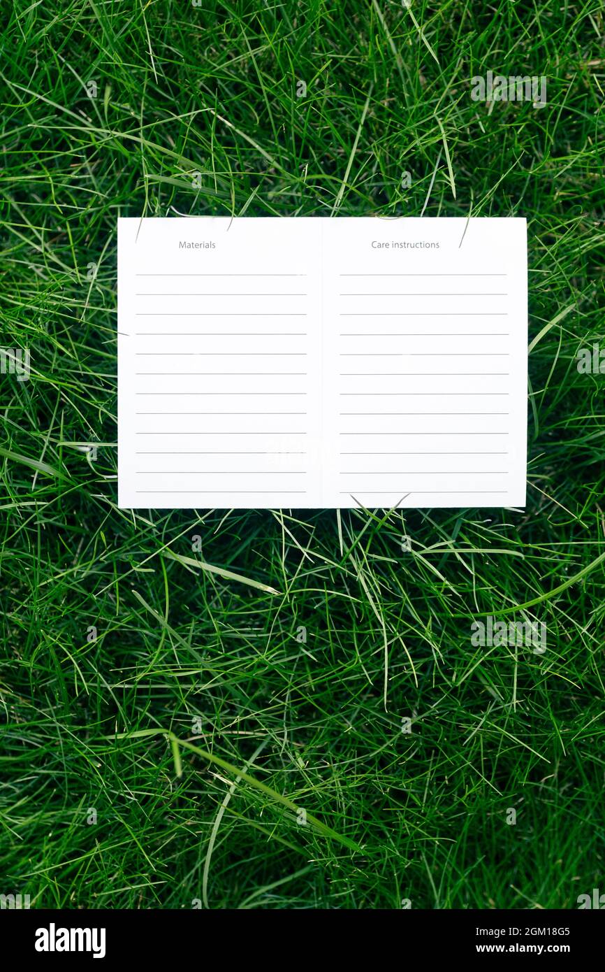 Top view of one white cardboard blank instructions for care and materials mock-up of lawn green grass with tag for logo Stock Photo