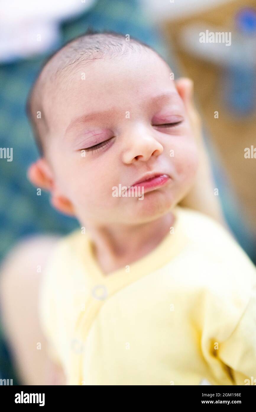 Newborn baby sleeping while parent holding it. Shallow depth of field portrait of cute baby Stock Photo