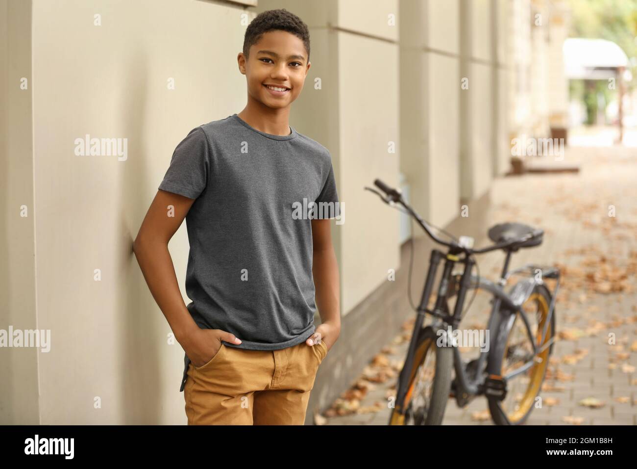 Charming African-American teenager with bicycle on city street Stock Photo