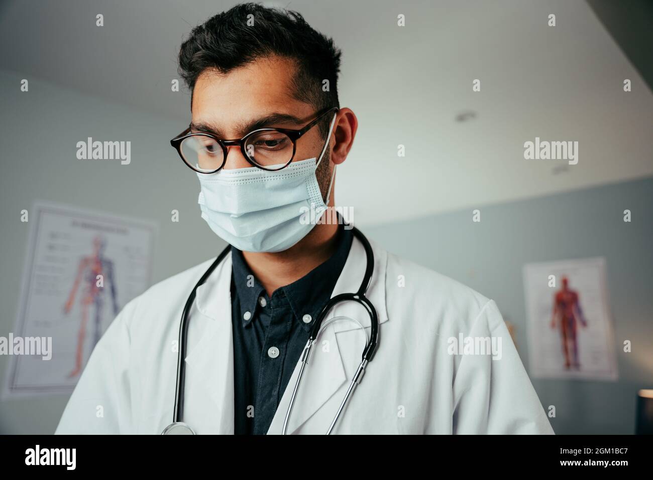 Mixed race male doctor wearing glasses working n clinic Stock Photo