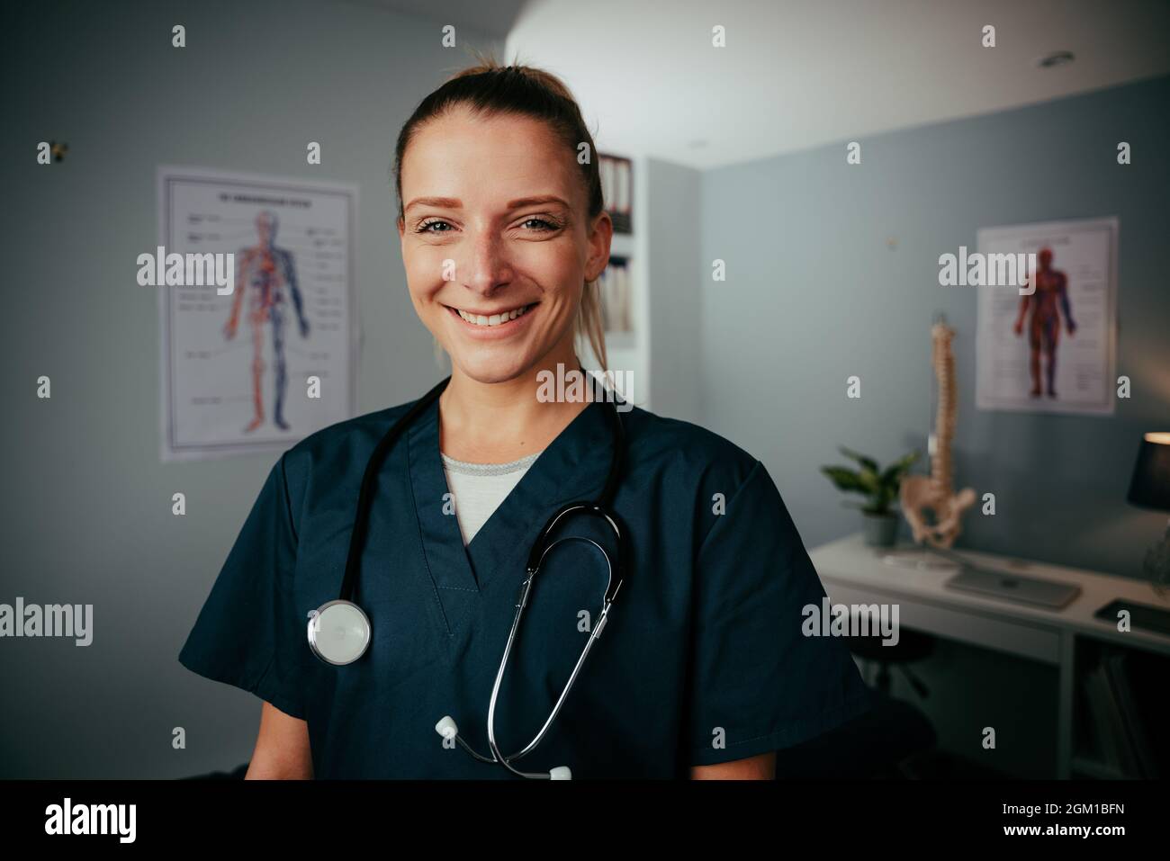 Caucasian female nurse smiling standing in doctors office  Stock Photo