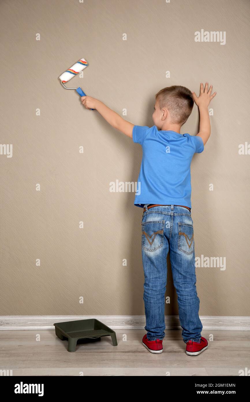 Cute little boy painting wall in room Stock Photo Alamy
