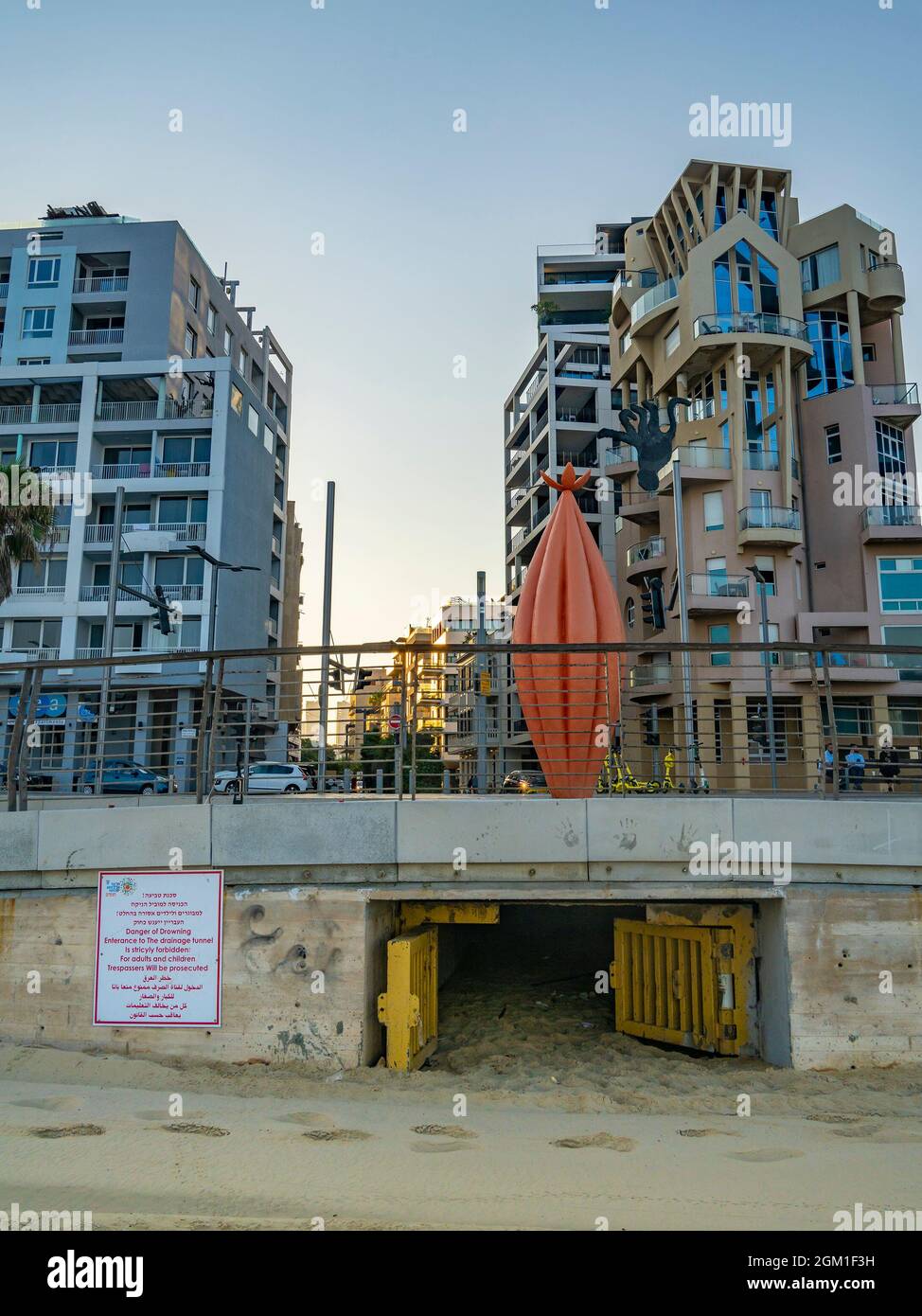 Tel Aviv, Israel - August 20th, 2021: An entrance to a drainage tunnel, under the buildings of Tel Aviv, Israel, with a multilingual warning sign. Stock Photo