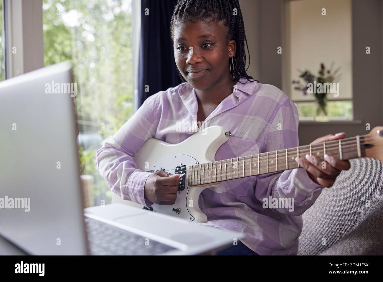 Teenage Girl At Home Learning To Play Electric Guitar With Online Lesson On  Laptop Computer Stock Photo - Alamy