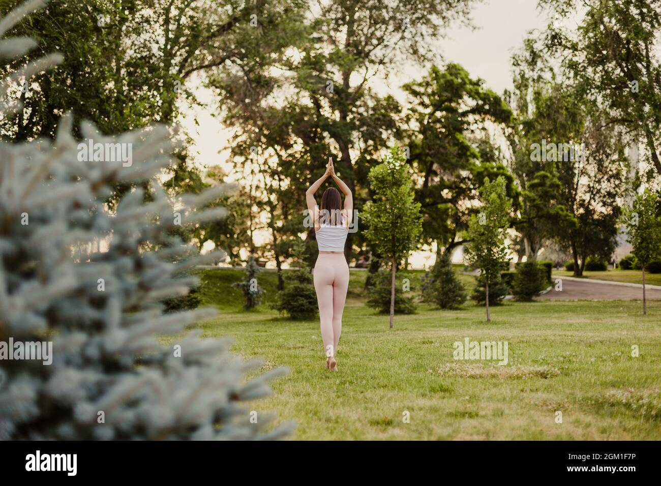 concept of peace and mental health, young woman in pink leggings stands in palm tree pose in yoga Stock Photo