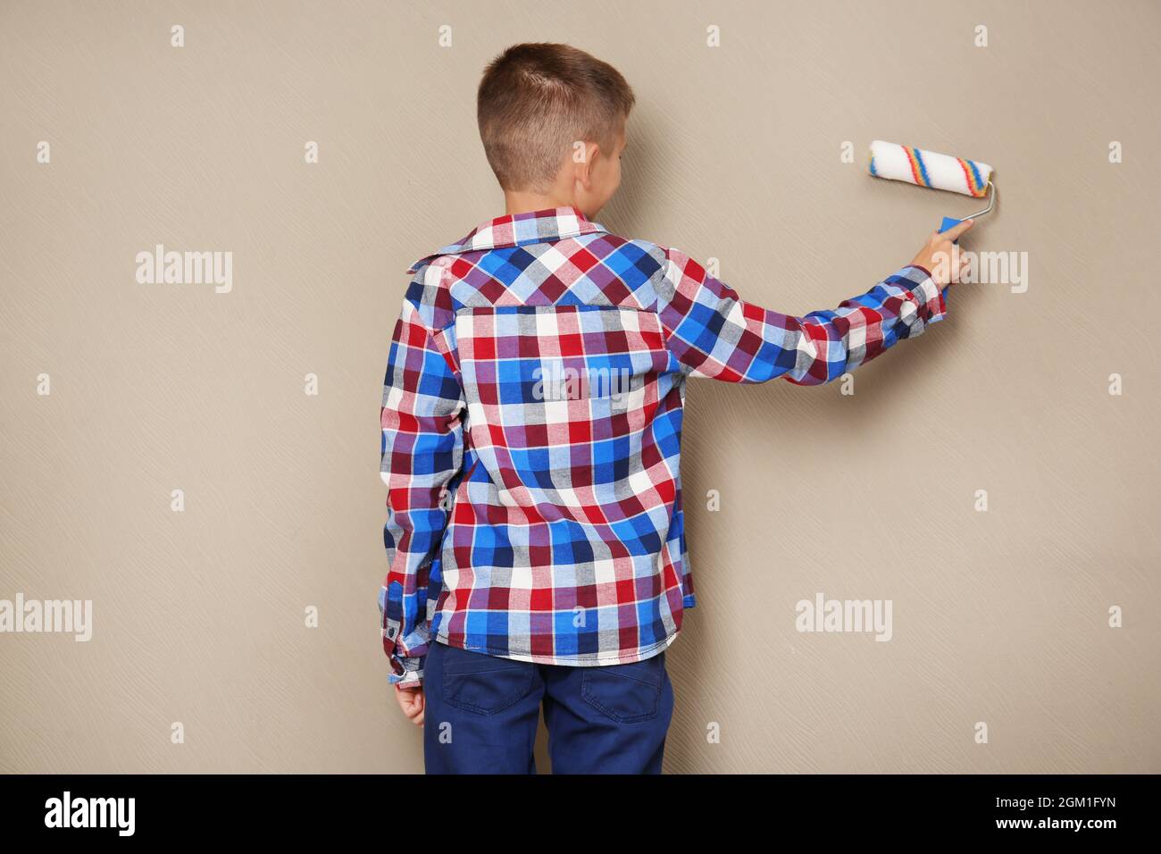 Cute little boy painting wall with roller Stock Photo Alamy