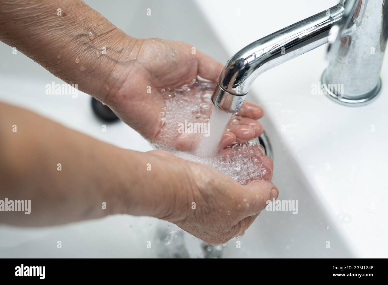 Asian senior elderly old lady woman patient washing hands in toilet bathroom the hospital ward