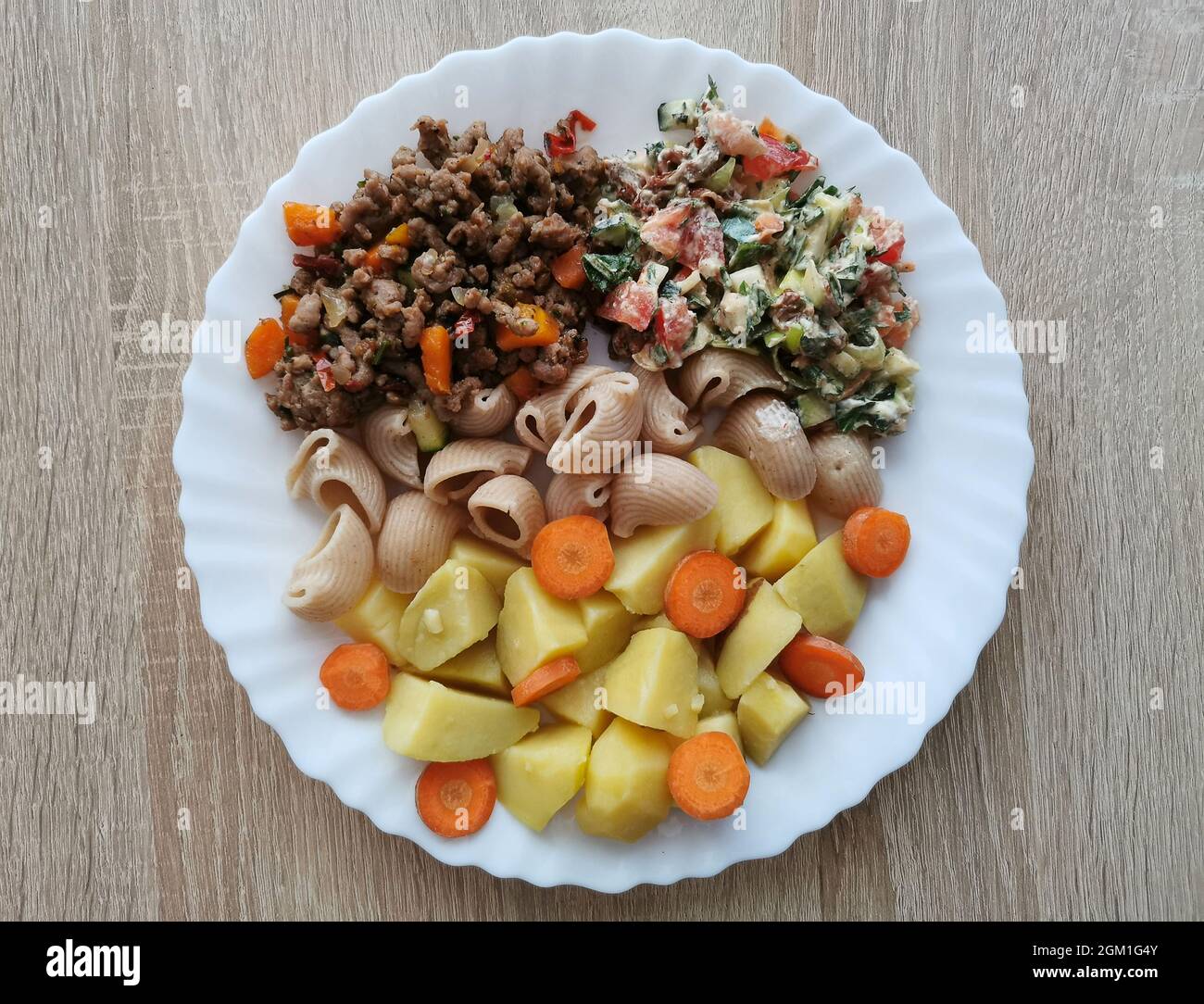 Whole grain pasta with potatoes, carrots and a vegetable salad Stock Photo