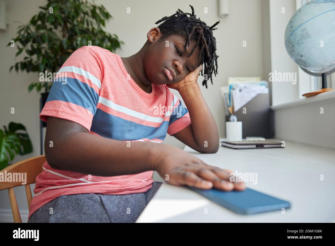 Teenage Boy Taking A Break From Social Media After Abuse And Bullying Laying Mobile Phone Down On Table Stock Photo