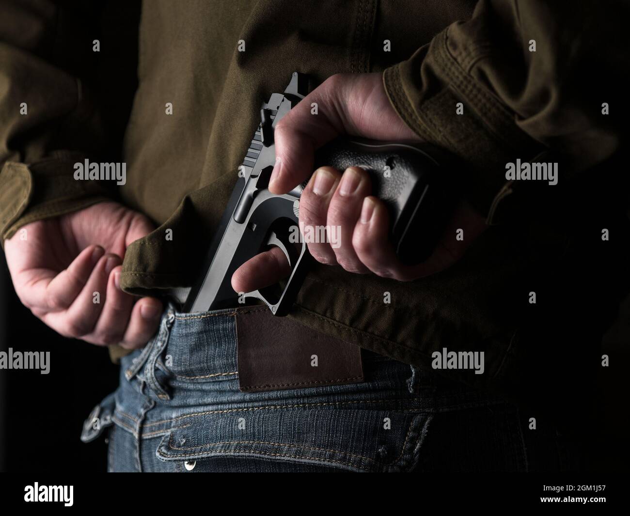 Man hiding a gun behind his back, hidden threat concept Stock Photo Alamy