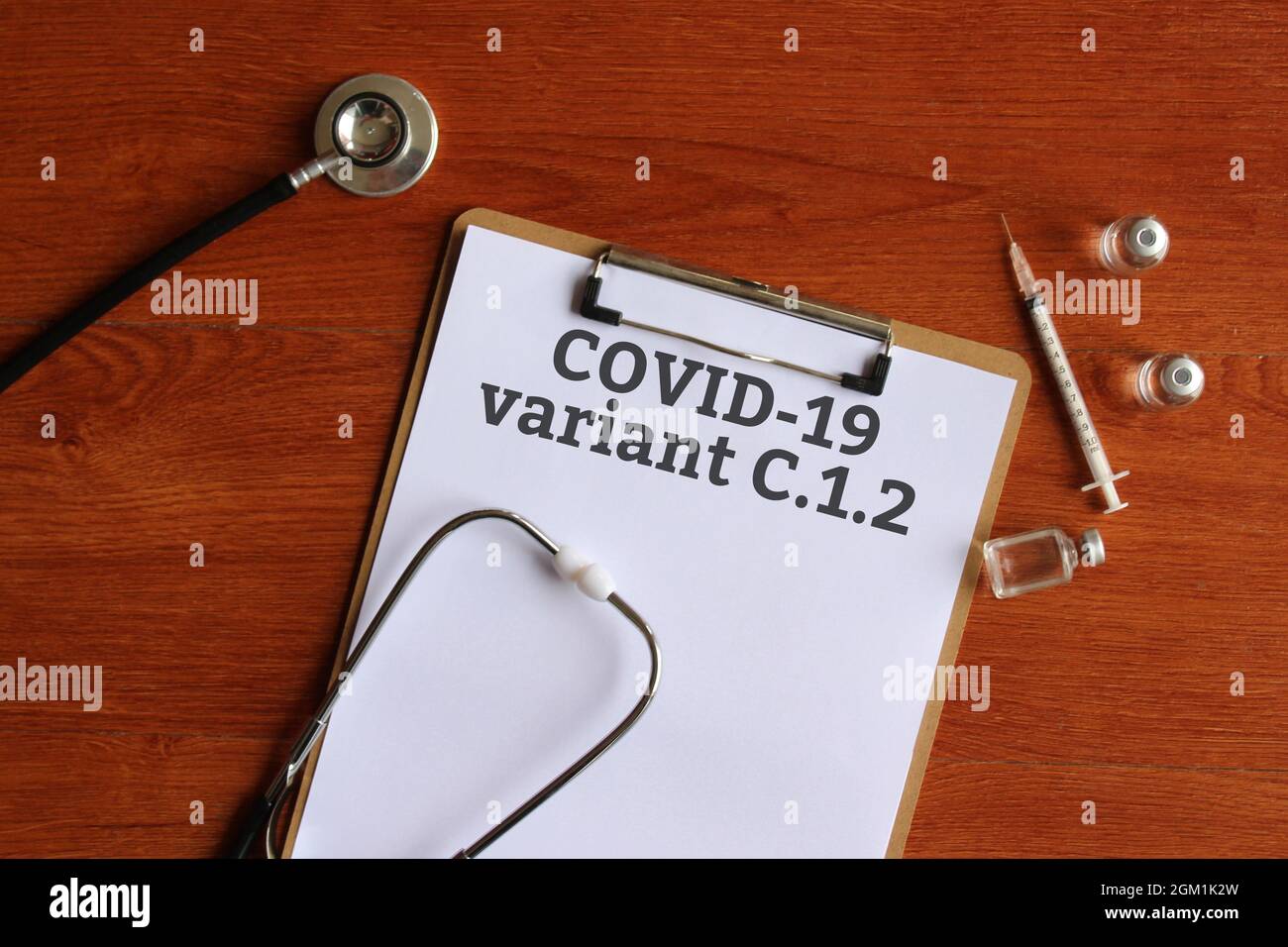 Medical concept. Top view of paper clipboard with text Covid-19 variant C.1.2, stethoscope, glass vial and syringe. Stock Photo