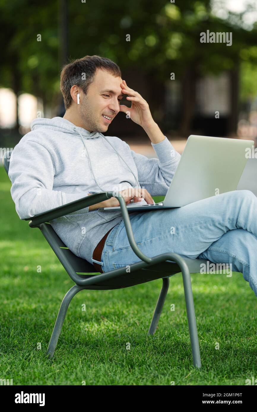 Blogger male work on computer in public park processes video for social ...