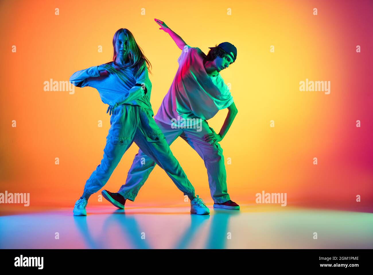 Two dancers, young girl and boy dancing hip-hop in casual sports youth  clothes on gradient multi colored background at dance hall in neon light  Stock Photo - Alamy
