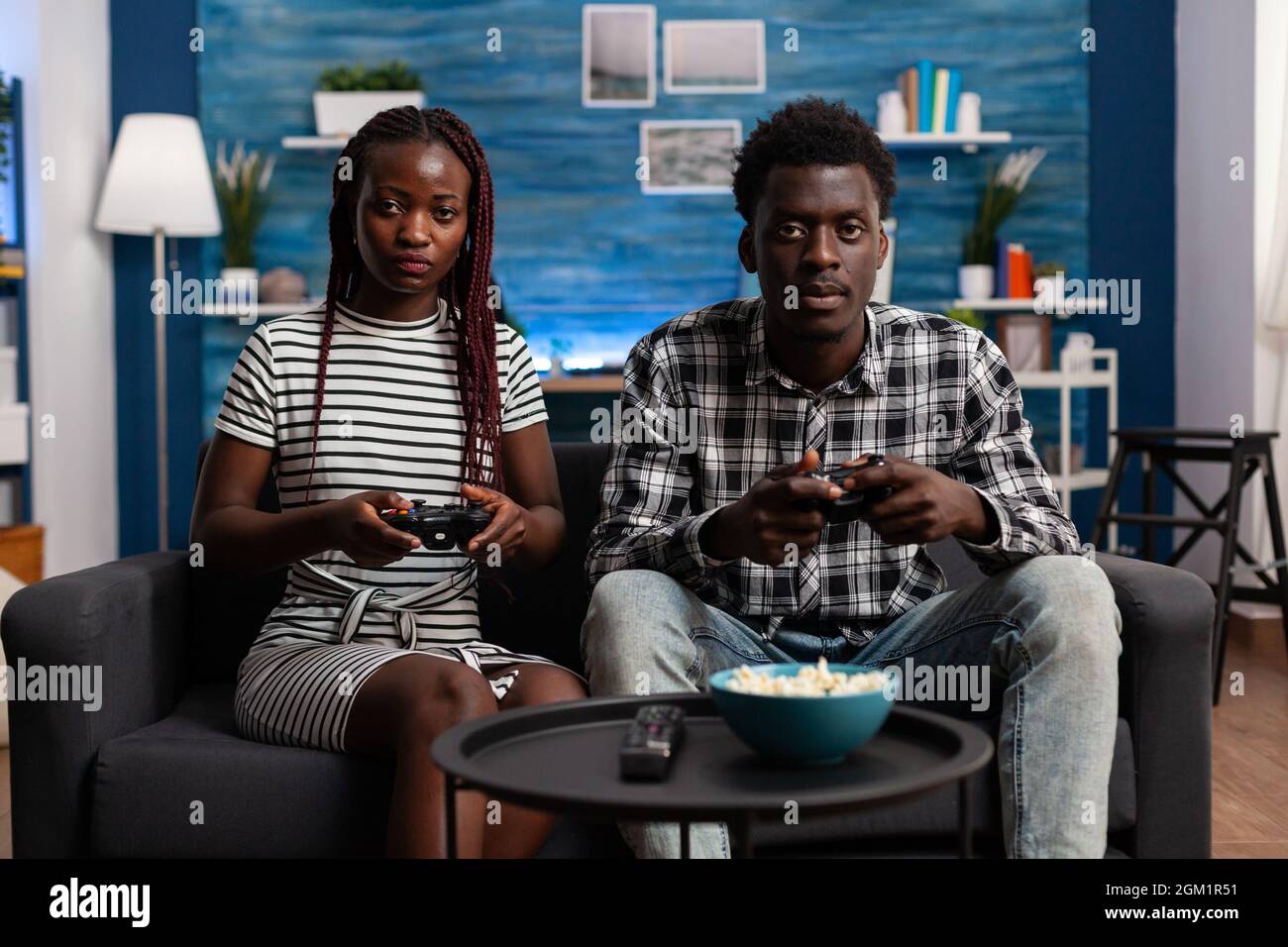 African american couple playing video game on TV console using joysticks at television display. Black married partners enjoying modern virtual game for fun and entertainment at home Stock Photo