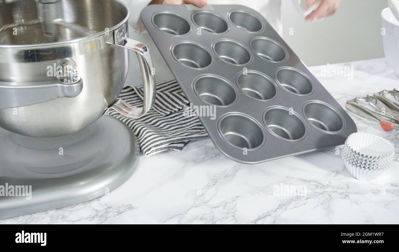 Step by step. Scooping batter with batter scooper into cupcake pan lined  with paper cupcake liners Stock Photo - Alamy