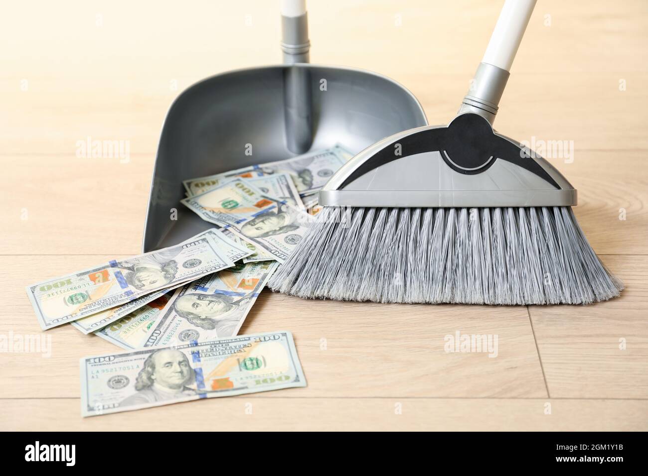 Broom sweeping dollars into dustpan Stock Photo Alamy