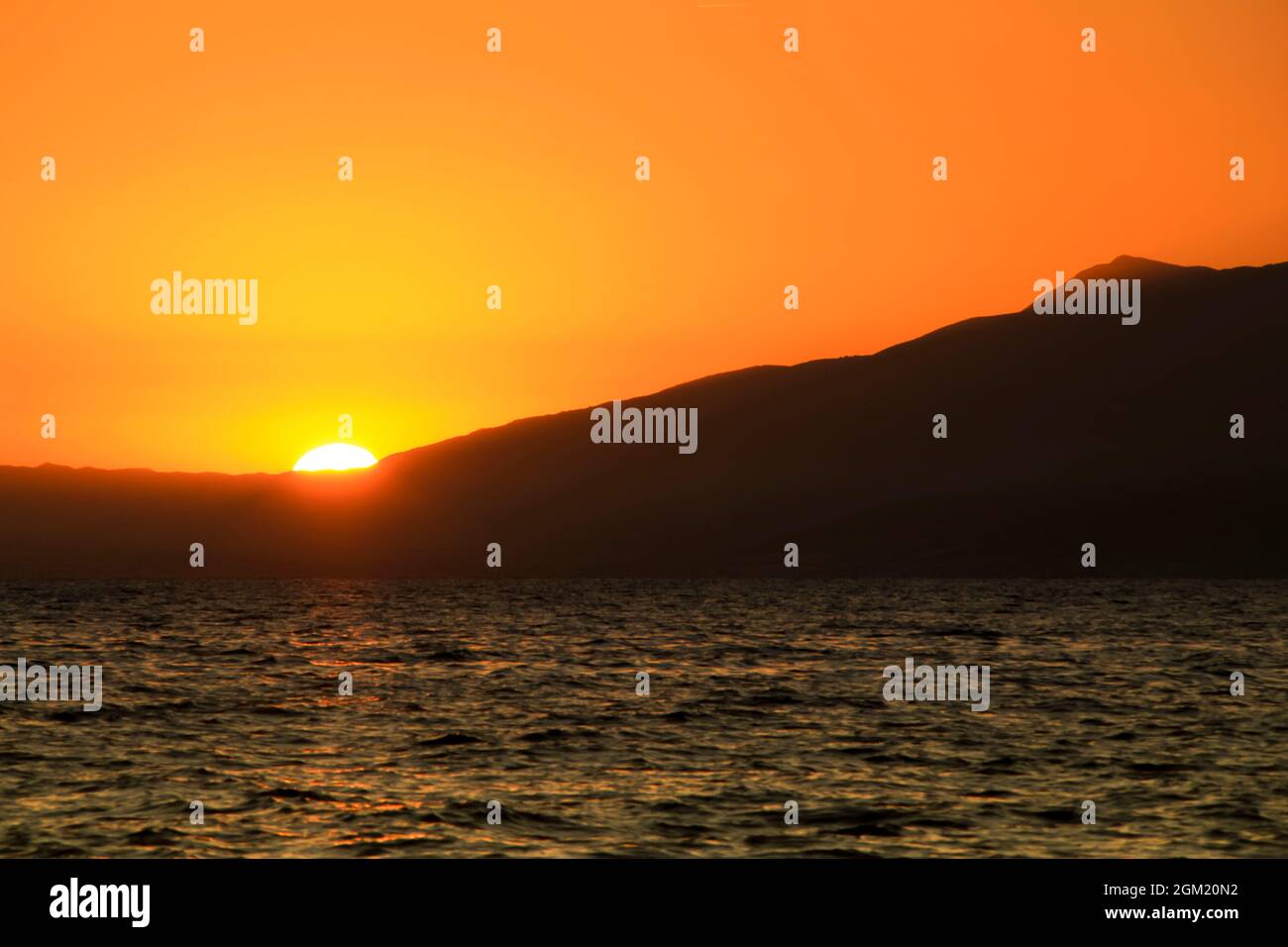Seascape with mountains and orange sky at sunset in Cabo de Gata, Almeria, Spain Stock Photo