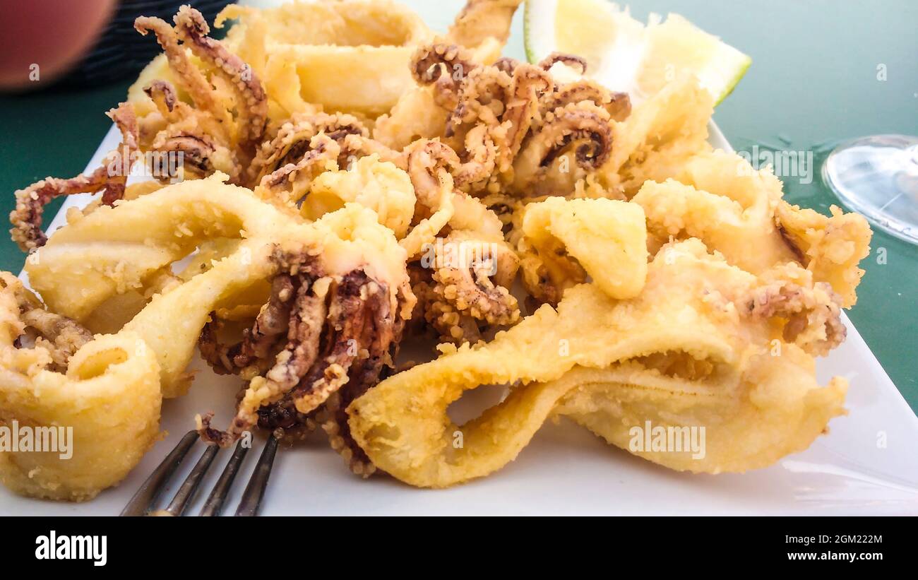 Typical Spanish tapa of battered fried squids with lemon in a restaurant Stock Photo