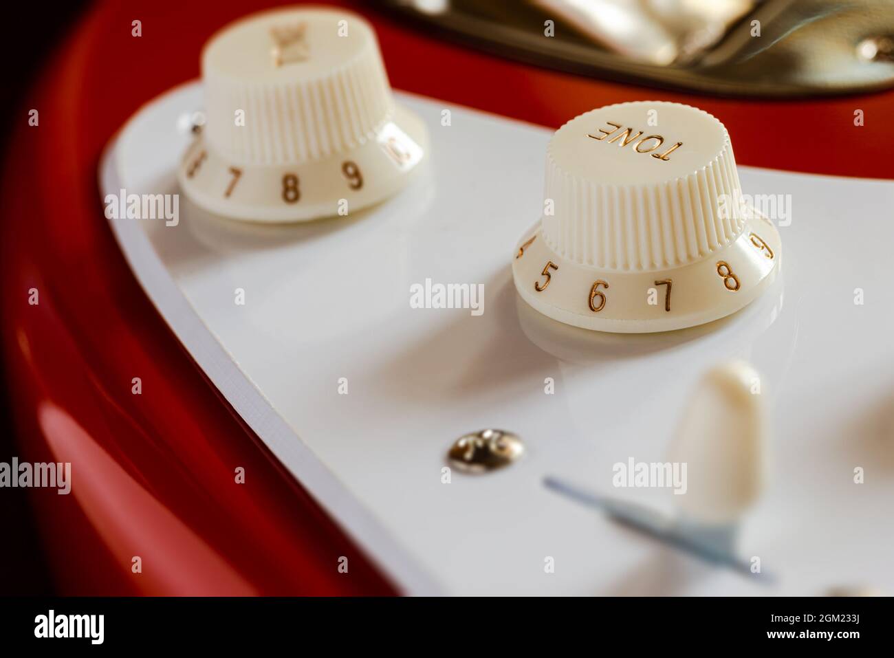 Detail of the volume and tone knobs of a red electric guitar Stock Photo