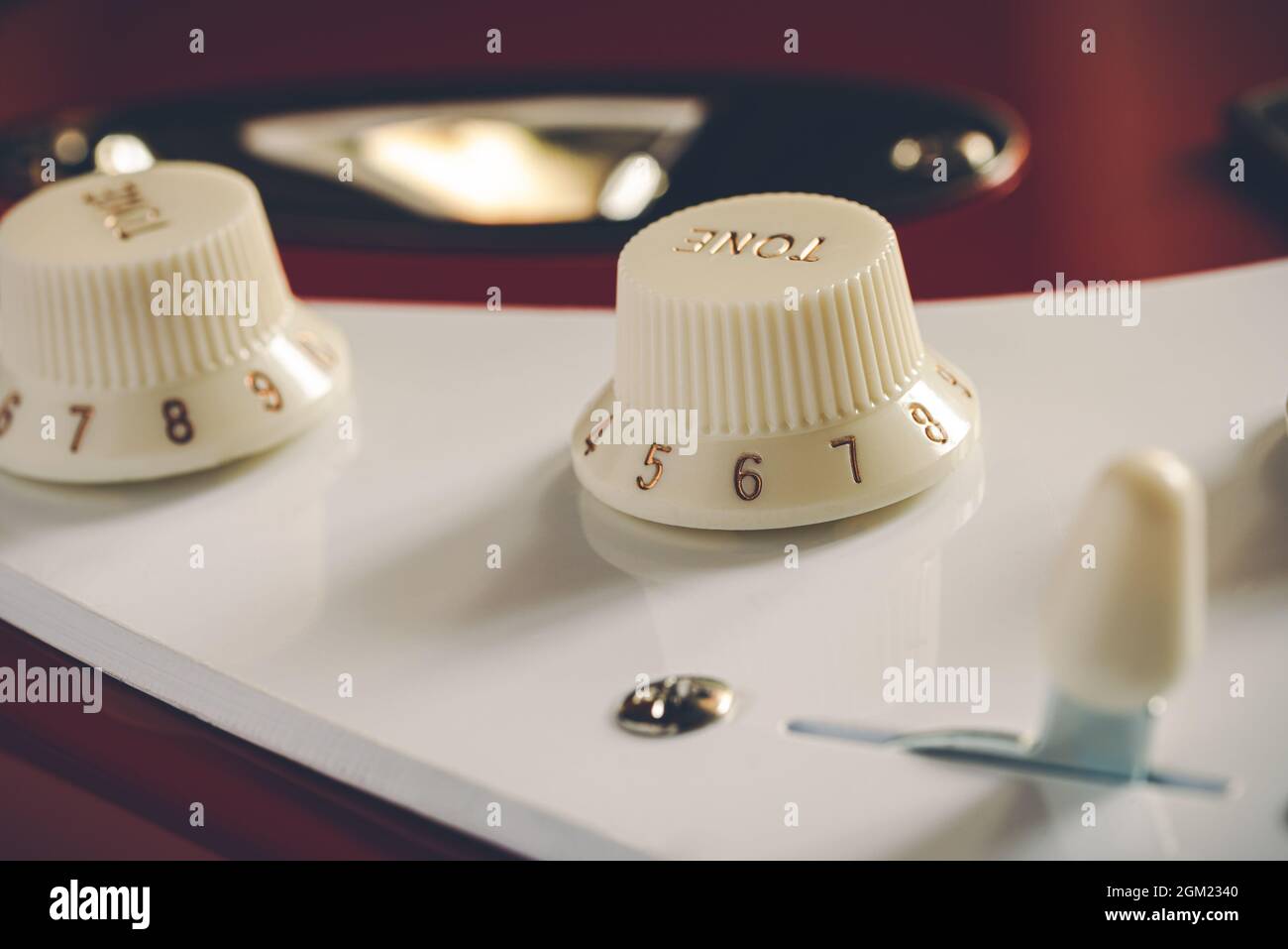 Detail of the volume and tone knobs of a red electric guitar Stock Photo