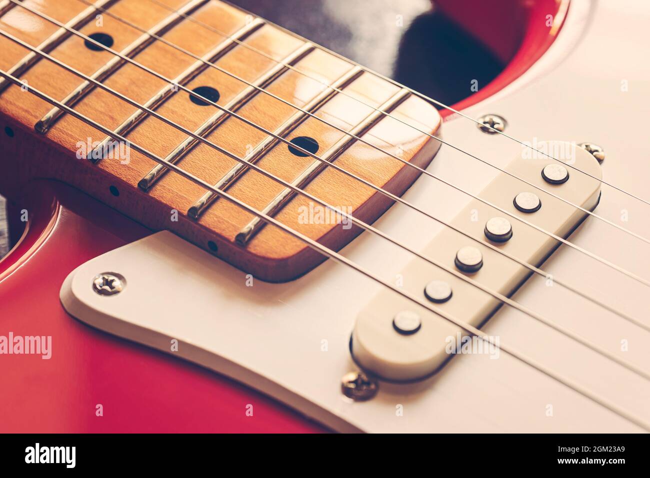 Detail of the neck, the pickup and the strings of a red electric guitar Stock Photo
