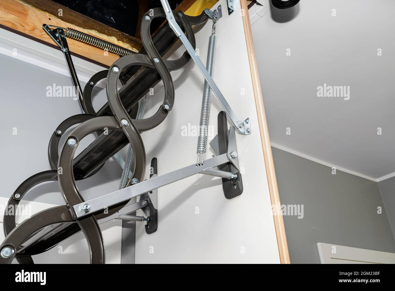A spring tensioning mechanism that facilitates the opening of a metal ladder to the attic, as well as hinges and stabilizers, located in the ceiling o Stock Photo