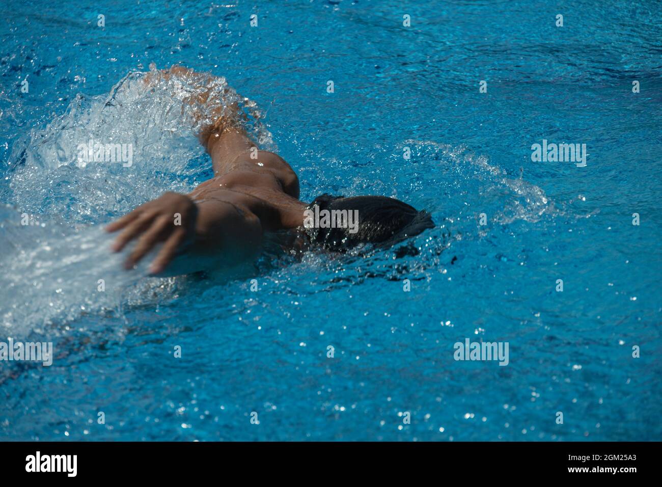 detail of a young man in swimming trunks swimming with his arms in a swimming pool Stock Photo