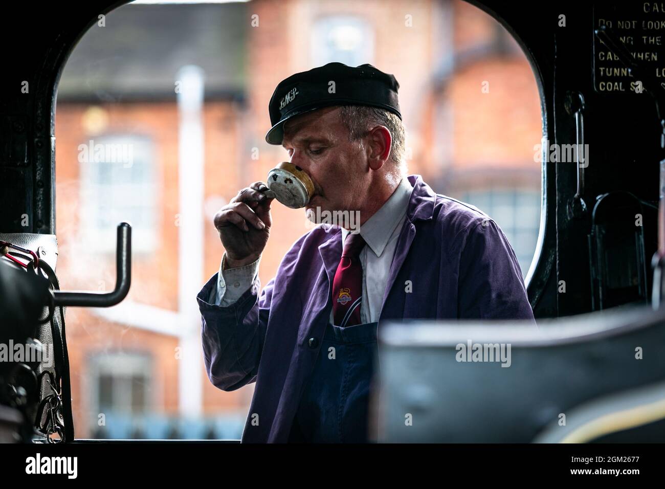 Kidderminster, Worcs, UK. 16th Sep, 2021. A steam train driver is silhouetted in his cab as he has a cup of tea from his tea can before embarking on a day's travel on the opening day of the Severn Valley Railway's Autumn Steam Gala, Kidderminster, Worcestershire. The gala lasts until Sunday 19th September and features guest locos. Credit: Peter Lopeman/Alamy Live News Stock Photo
