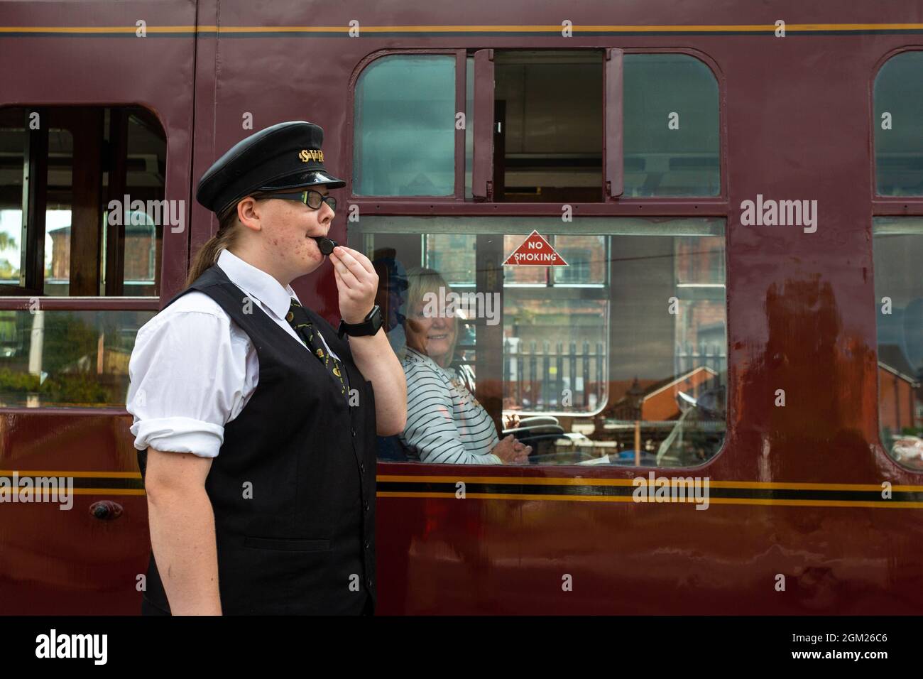Kidderminster, Worcs, UK. 16th Sep, 2021. Volunteer steam train dispatcher Kaylie Armishaw blows her whistle as a steam train embarks on a day's travel on the opening day of the Severn Valley Railway's Autumn Steam Gala, Kidderminster, Worcestershire. The gala lasts until Sunday 19th September and features guest locos. Credit: Peter Lopeman/Alamy Live News Stock Photo