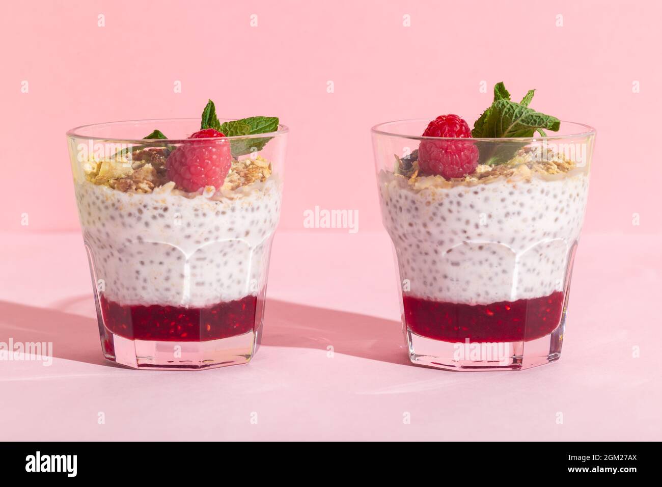 Chia seeds vanilla pudding with raspberry, oats musli and mint on rose hard shadow Stock Photo