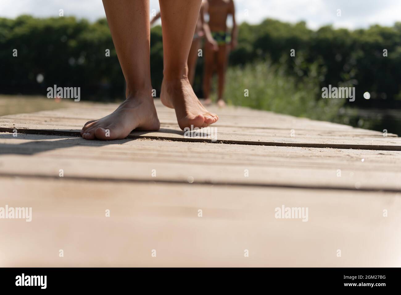 woman legs walking on a floating wooden dock in the river, followed by a  boy Stock Photo - Alamy