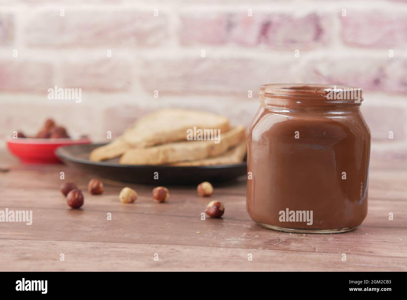 Chocolate Hazelnut in a container and bread on table  Stock Photo