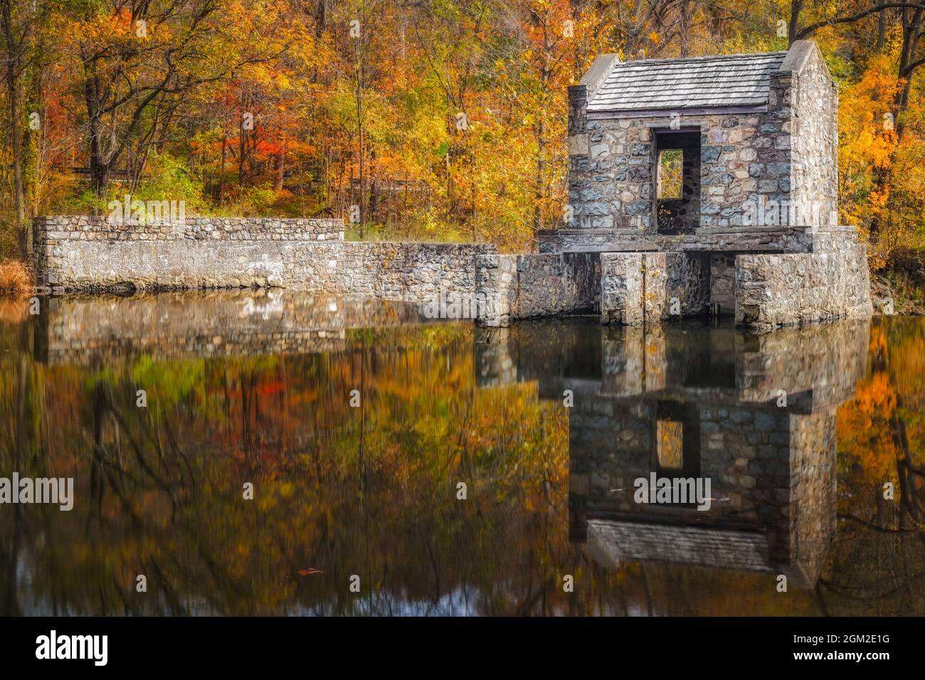 Speedwell Dam In Autumn - View to the stone structure on the Whippany River surround by the warm colors of the fall foliage.   This image is available Stock Photo