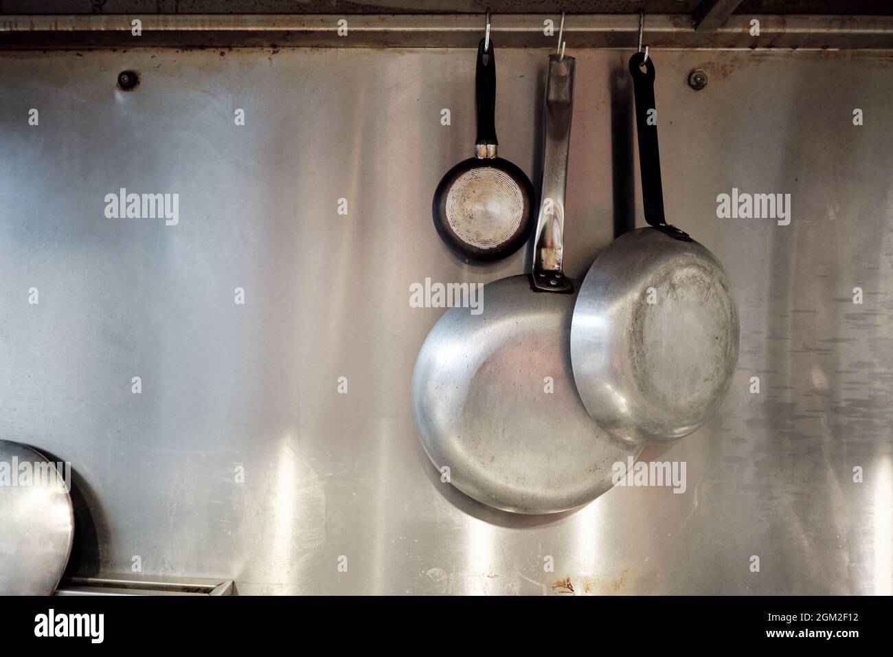 Metal frying pans hanging on a rack in an industrial restaurant kitchen  Stock Photo - Alamy