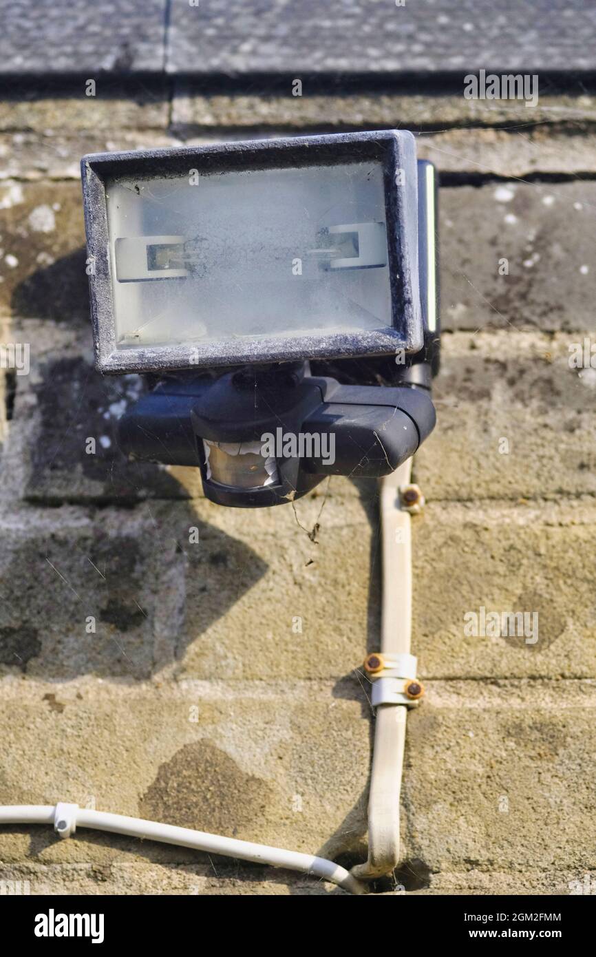 Broken down outdoor security light attached to brick wall Stock Photo