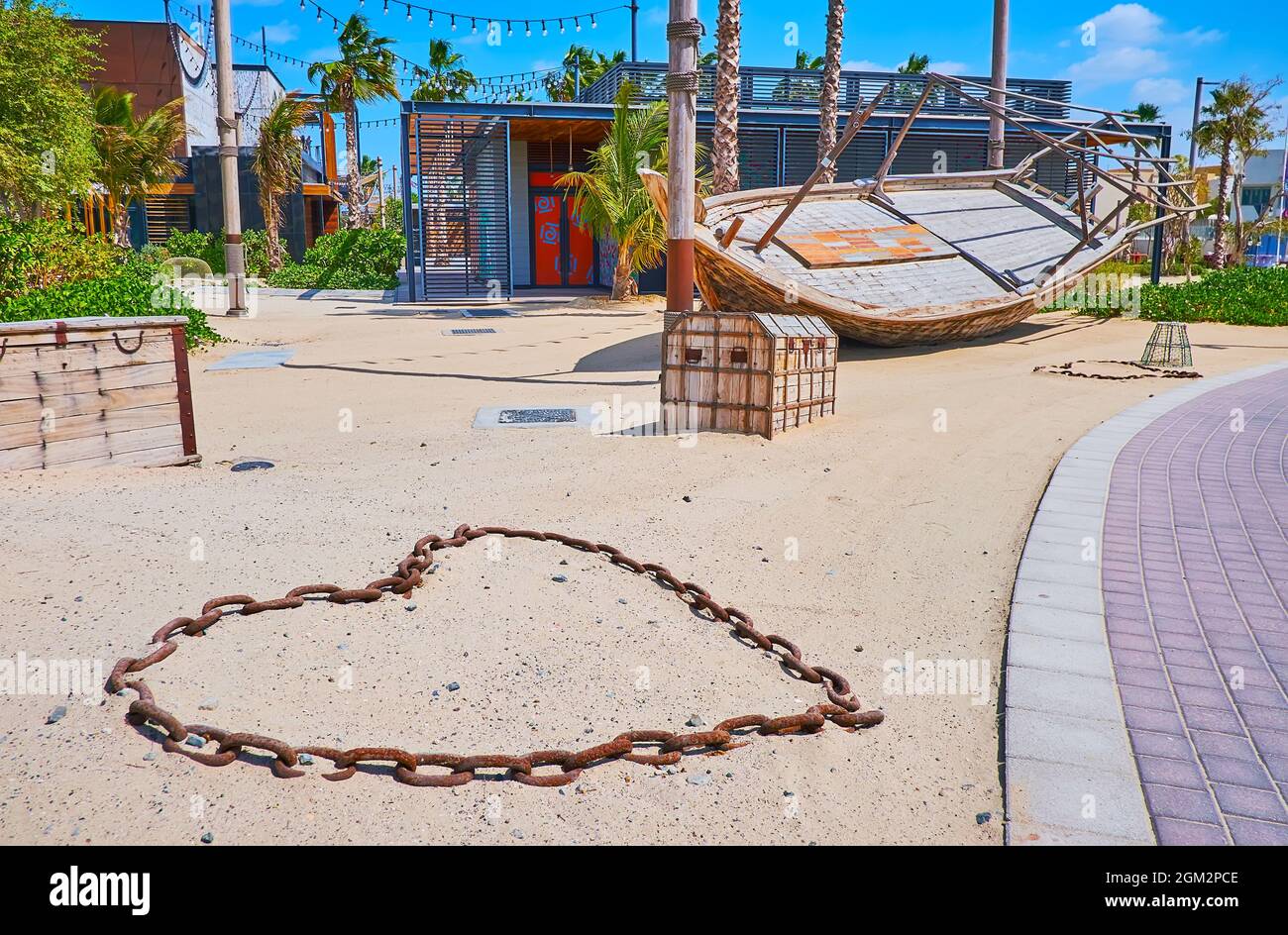 The promenade of La Mer beach is surrounded with scenic installations - heart of rusty chain, wooden treasure chests and the old fishing boat, Dubai, Stock Photo