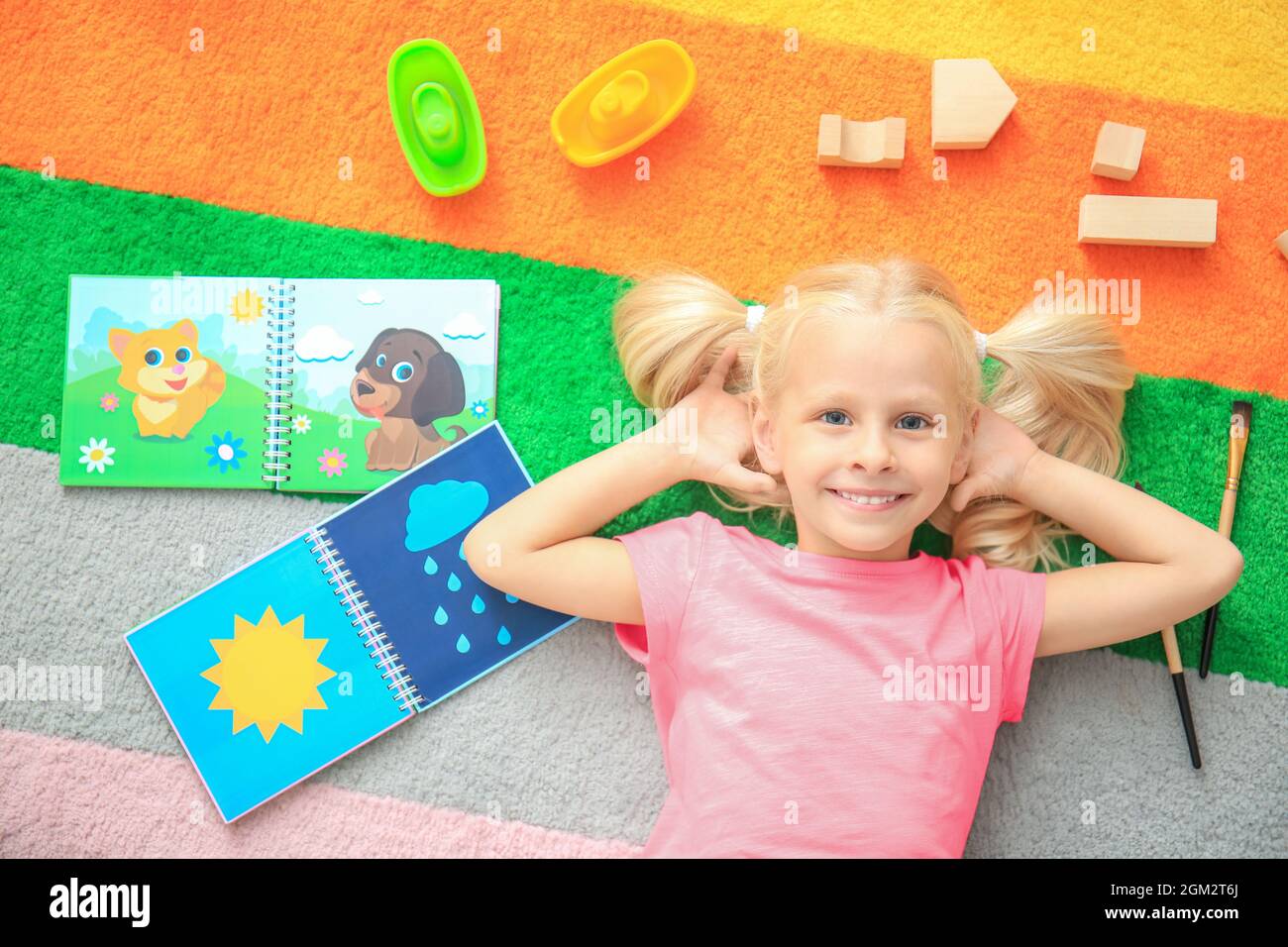 Cute little girl with toys on color carpet in kindergarten Stock Photo ...