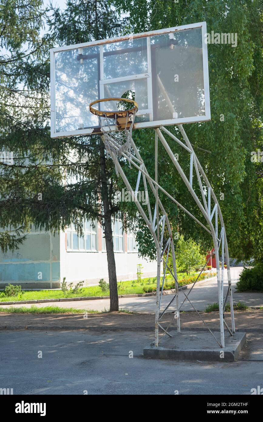 old torn basketball hoop at school grounds on summer day Stock Photo