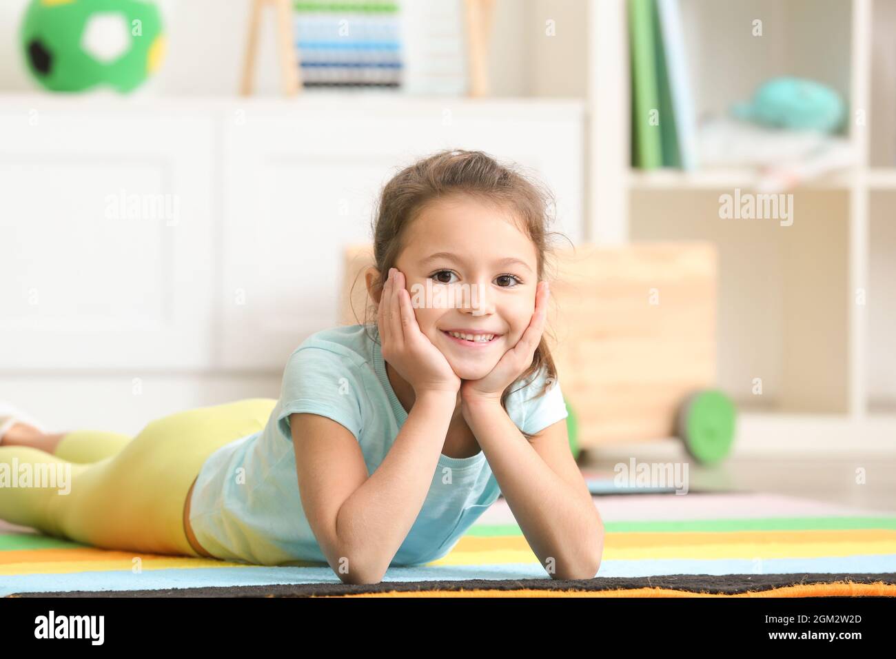 Cute little girl lying on floor in kindergarten Stock Photo Alamy