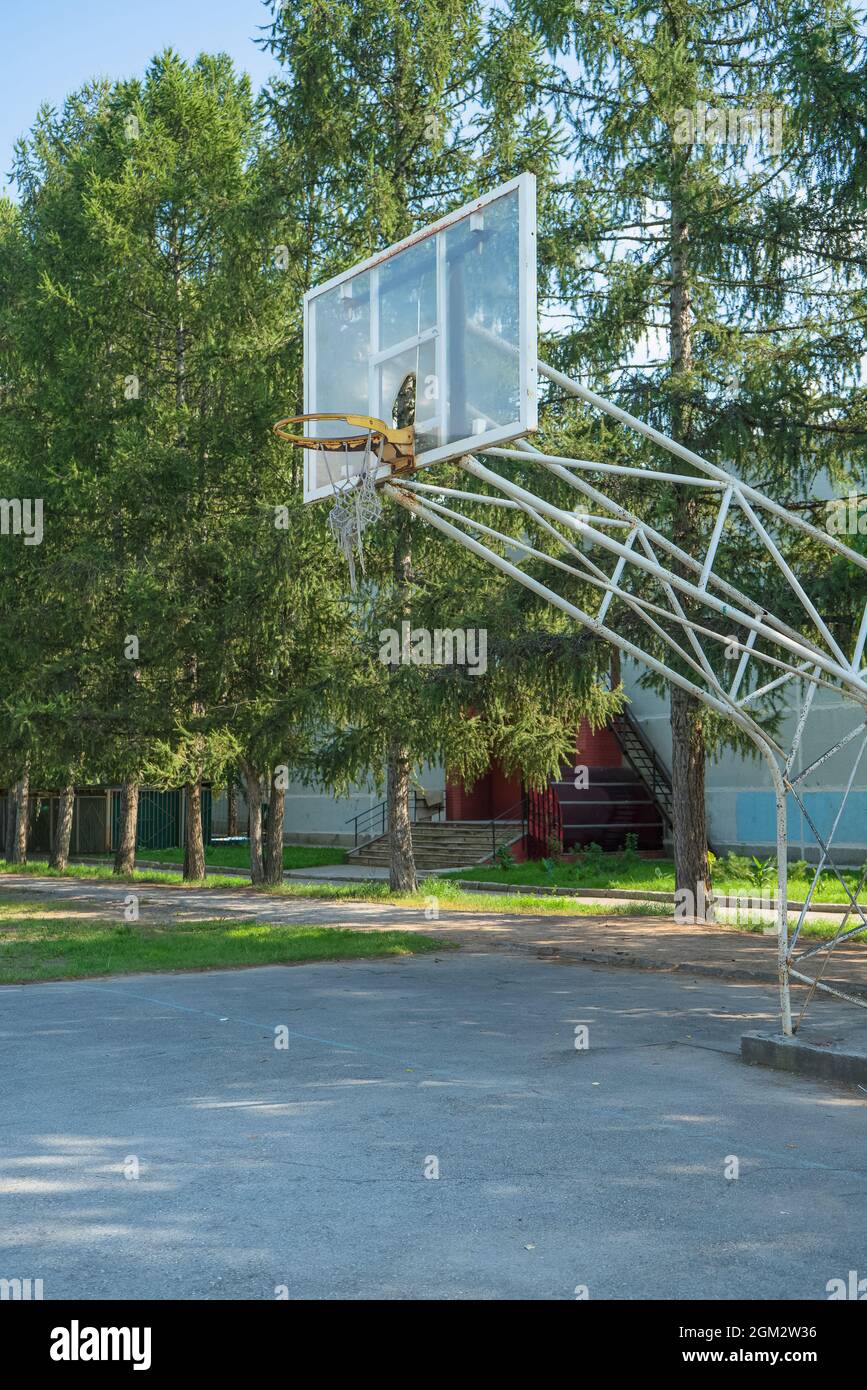 torn and partly broken basketball ring on sunny summer day at school grounds Stock Photo