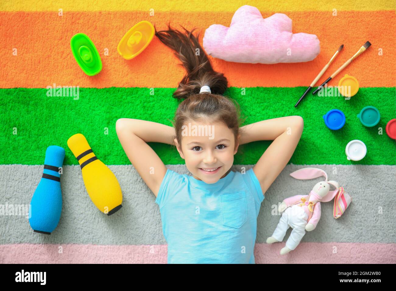 Cute little girl with toys on color carpet in kindergarten Stock Photo ...