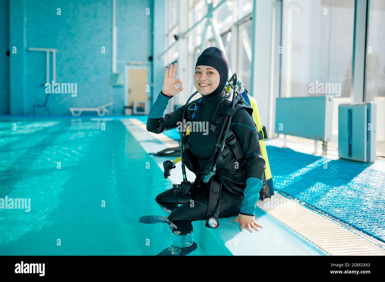 Female diver in scuba suit sitting at the poolside Stock Photo