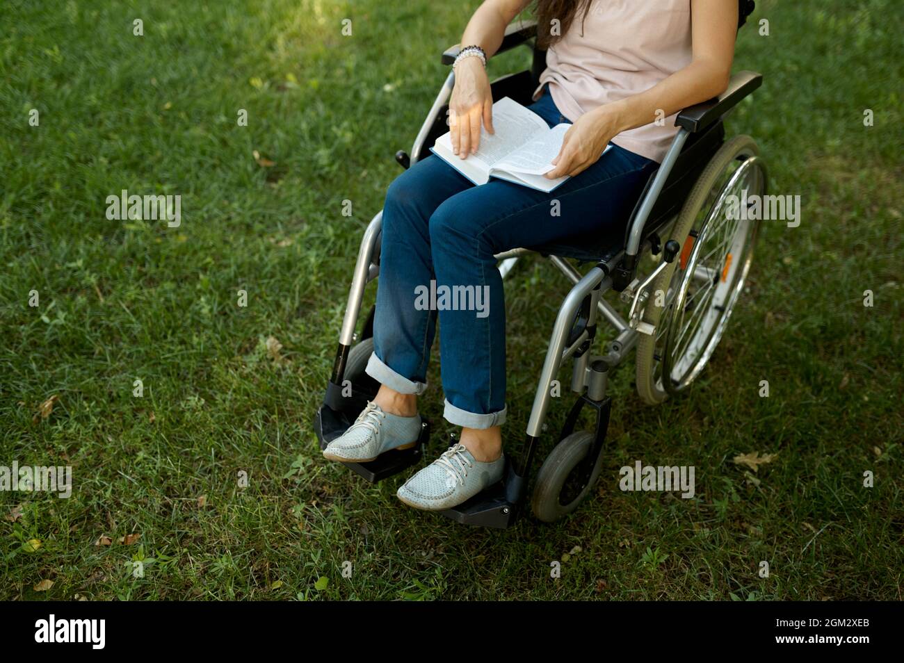 Disabled woman in wheelchair reading book in park Stock Photo Alamy
