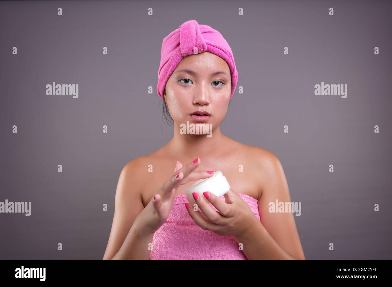 young chinese woman taking care of her skin isolated from grey background, beauty concept Stock Photo