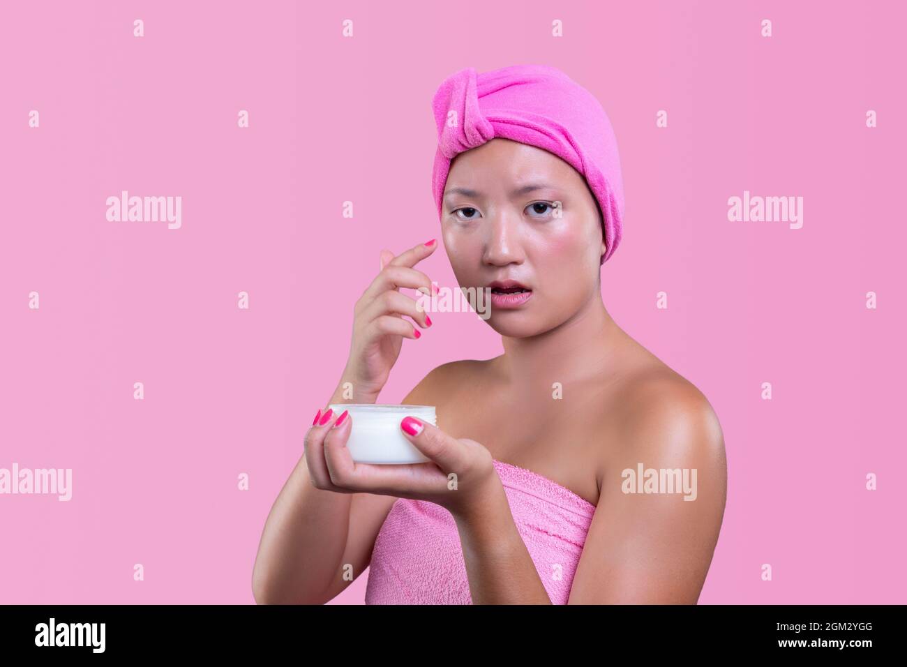young chinese woman taking care of her skin isolated from pink background, beauty concept Stock Photo