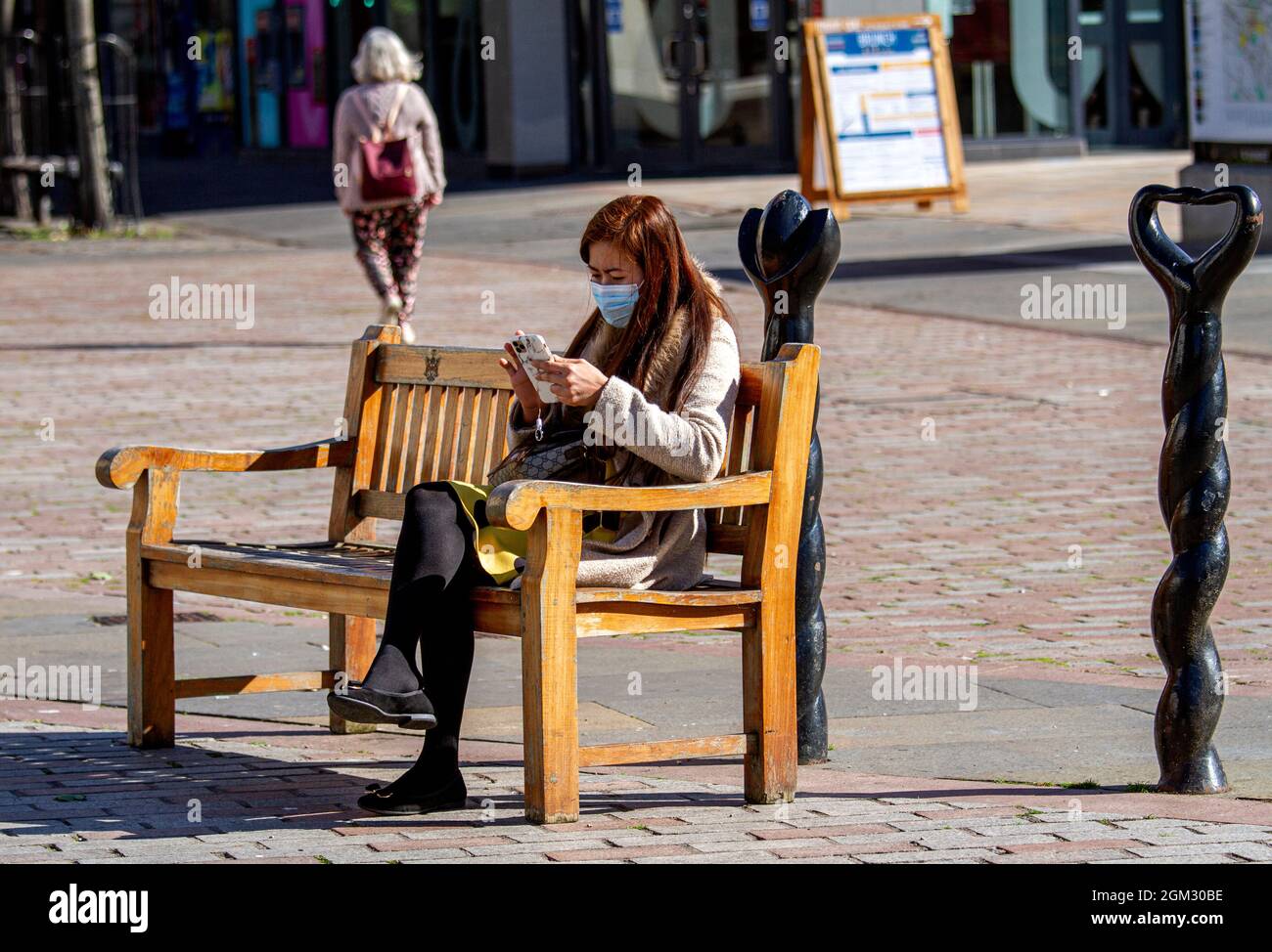 Dundee, Tayside, Scotland, UK. 16th Sep, 2021. UK weather: Warm mid September sunshine across North East Scotland with temperatures reaching 19°C. A South East Asian woman wearing a facemask spending the day out enjoying the glorious warm sunny weather whilst texting messages on her mobile phone in Dundee city centre. Credit: Dundee Photographics/Alamy Live News Stock Photo