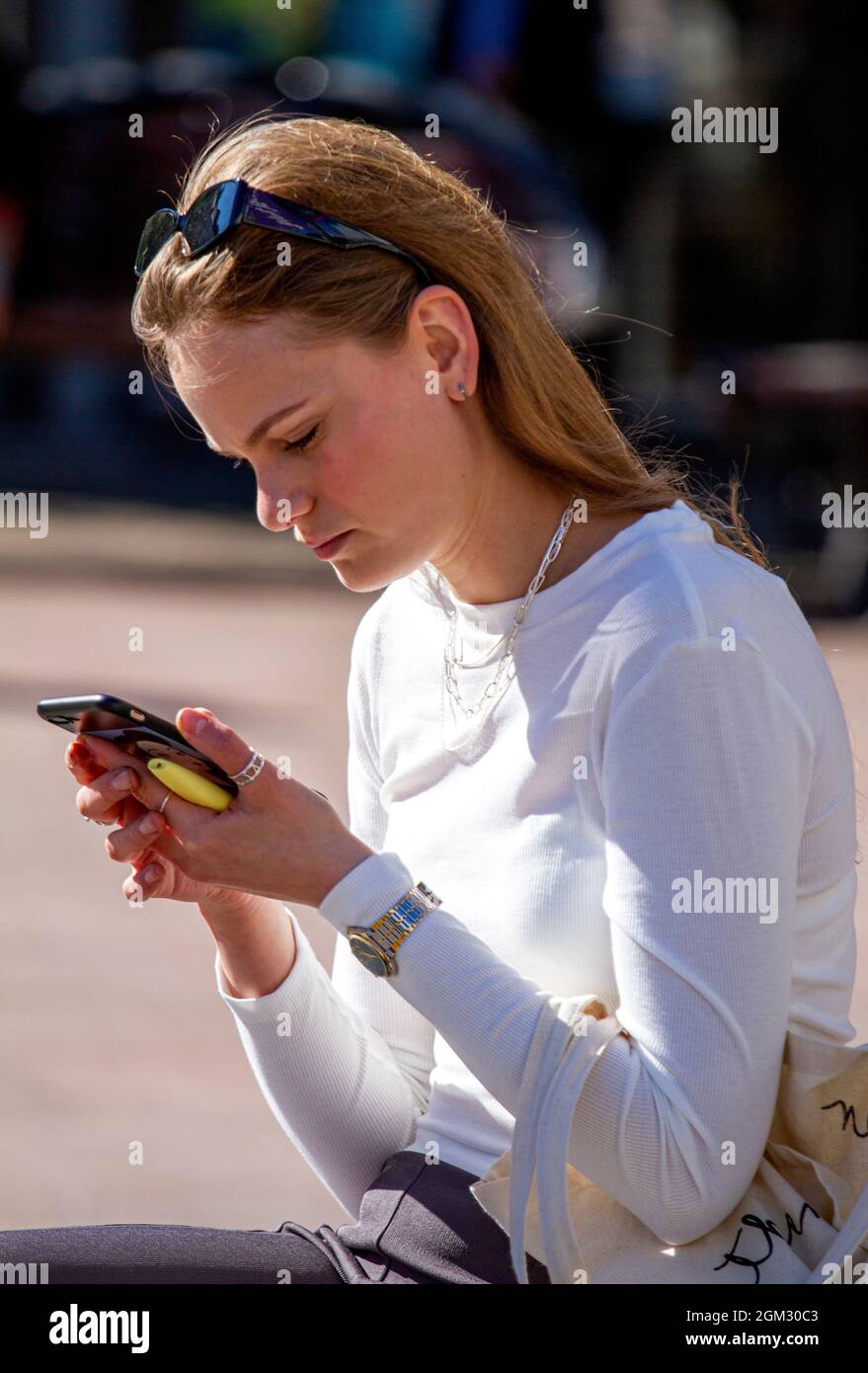 Dundee, Tayside, Scotland, UK. 16th Sep, 2021. UK weather: Warm mid September sunshine across North East Scotland with temperatures reaching 19°C. A glamorous young Polish woman spending the day out enjoying the glorious warm sunny weather whilst texting messages on her mobile phone in Dundee city centre. Credit: Dundee Photographics/Alamy Live News Stock Photo