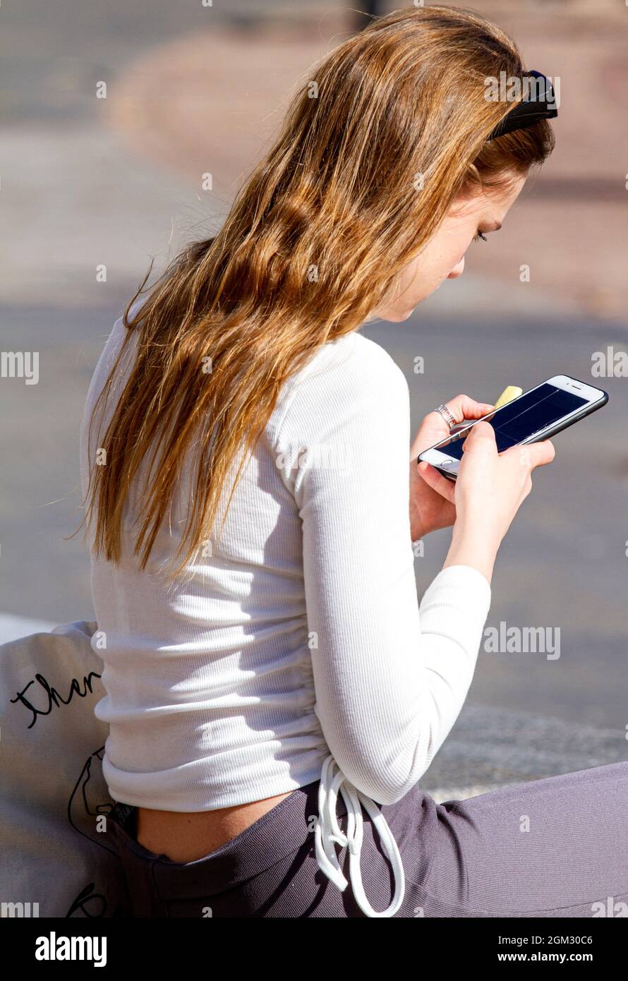 Dundee, Tayside, Scotland, UK. 16th Sep, 2021. UK weather: Warm mid September sunshine across North East Scotland with temperatures reaching 19°C. A glamorous young Polish woman spending the day out enjoying the glorious warm sunny weather whilst texting messages on her mobile phone in Dundee city centre. Credit: Dundee Photographics/Alamy Live News Stock Photo