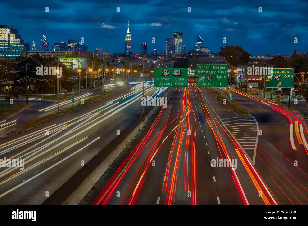 Path To And From NYC - Vehicular light trails from route 3 in New Jersey lead to a view of the New York City skyline.   Showcased is the iconic landma Stock Photo