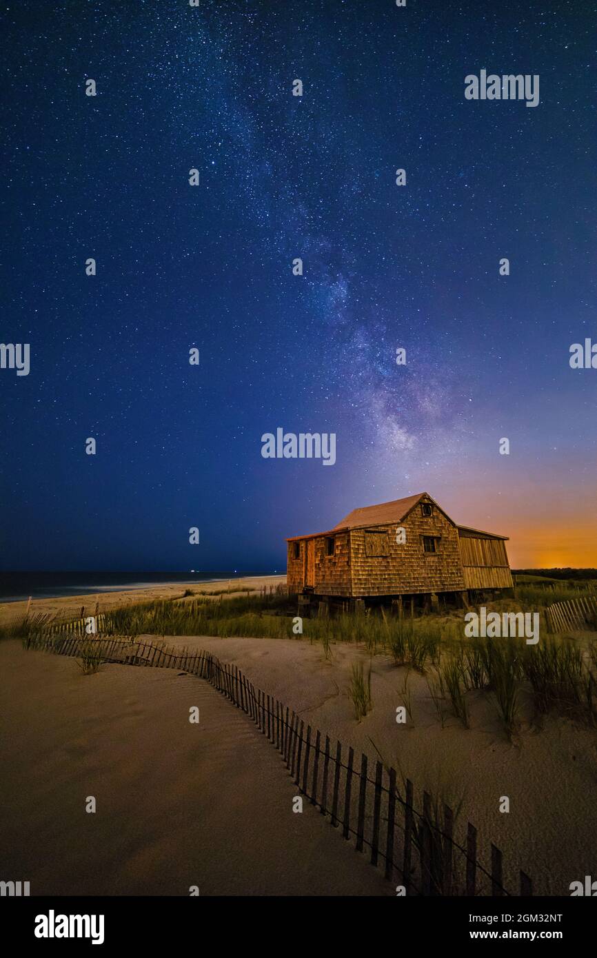 Jersey Shore Setting Moon  and Milky Way - Island Beach State Park at the NJ Shore with beach fences leading to the Judge's Shack underneath a starry Stock Photo